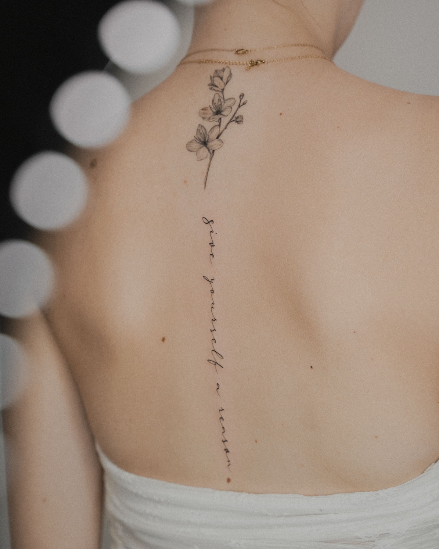Delicate botanical spine tattoo